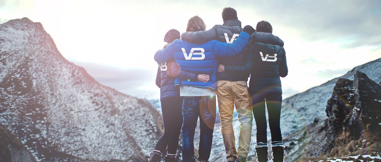 Fire VB medarbeidere ser ut mot fjell. Alle har jakker med VB logo på ryggen